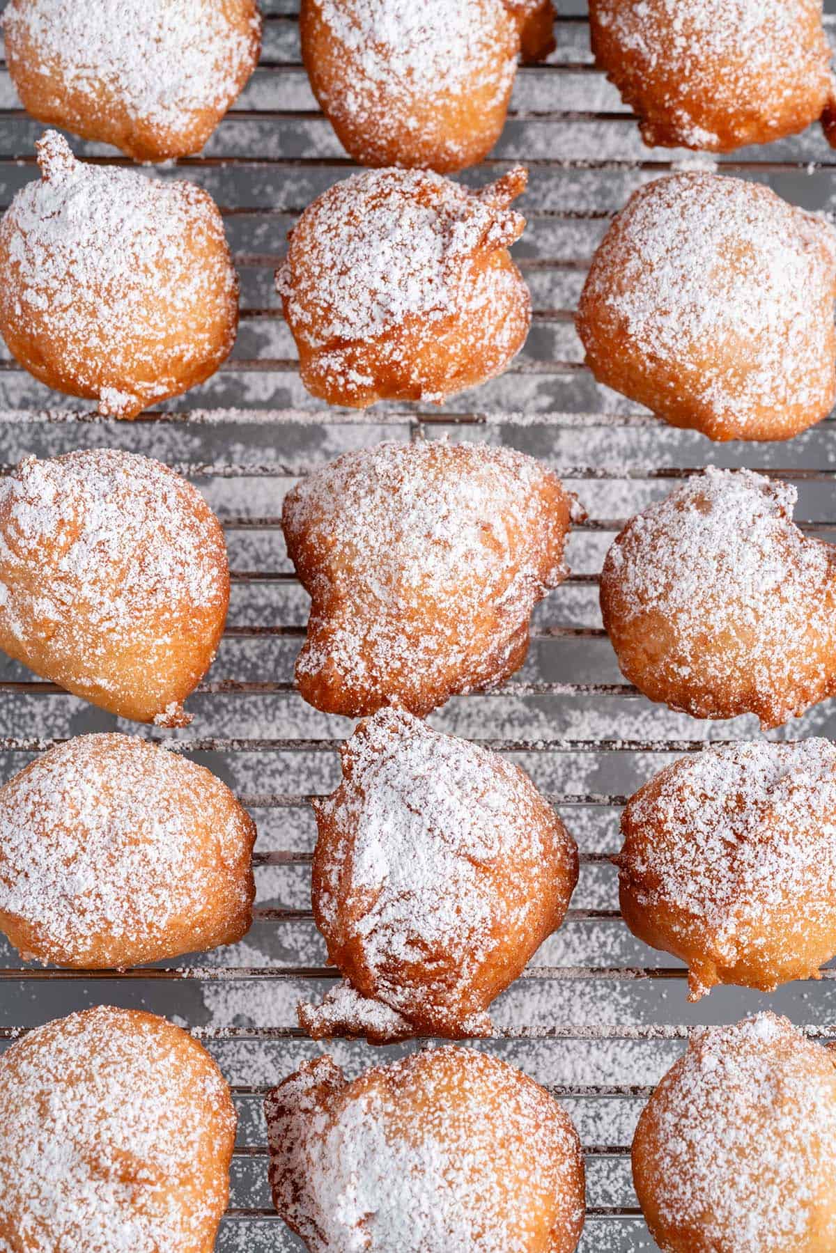 vegan zeppole dusted with powdered sugar on cooling rack