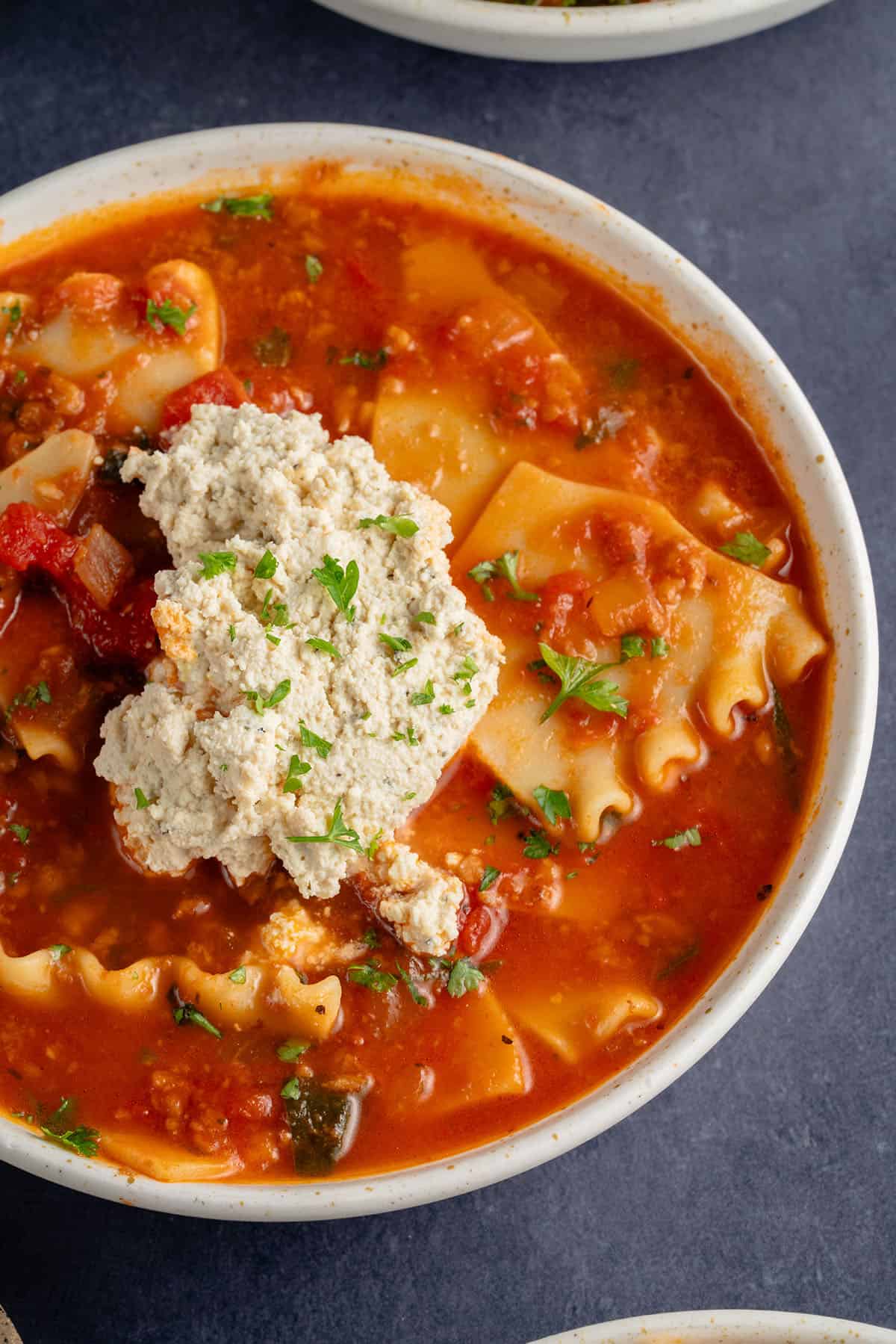 bowl of lasagna soup topped with ricotta and parsley