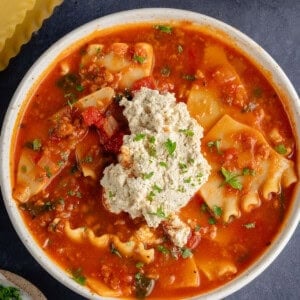 bowls of lasagna soup topped with ricotta and parsley