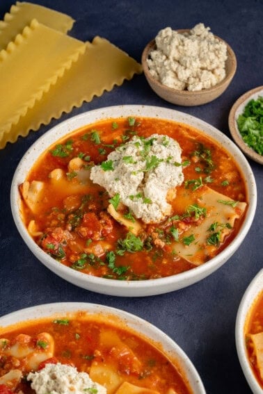 bowls of lasagna soup topped with ricotta and parsley