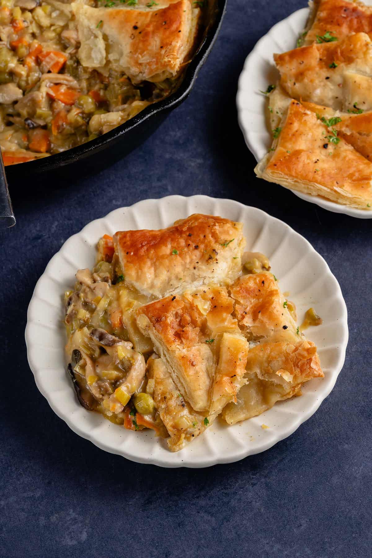 a small white scalloped plate of Vegan Mushroom Pot Pie with puff pastry on blue background