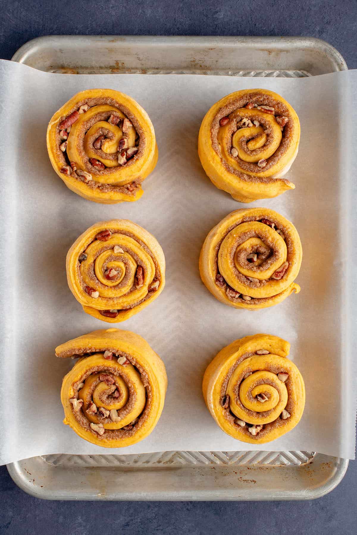 unbaked pumpkin cinnamon rolls on a baking sheet before rising