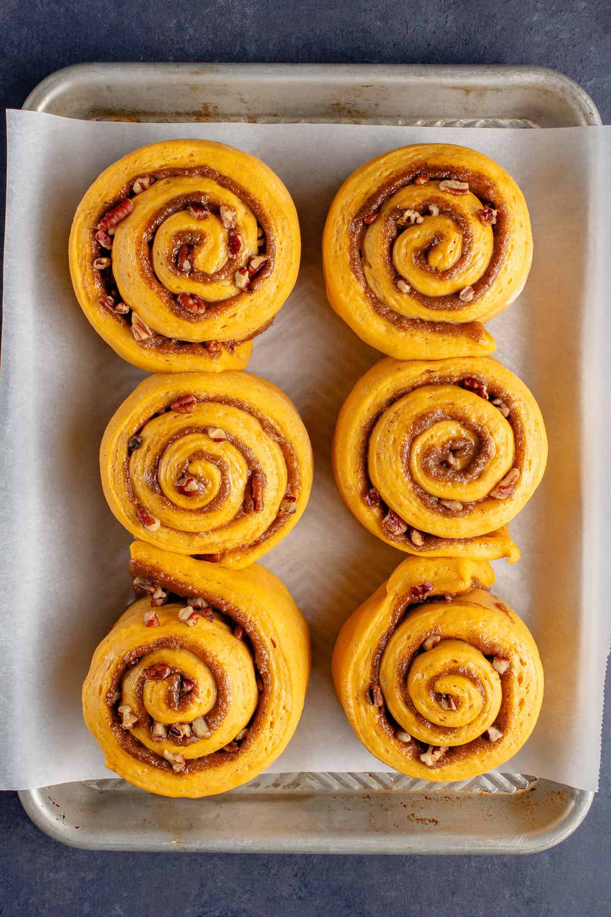 unbaked pumpkin cinnamon rolls on a baking sheet after rising