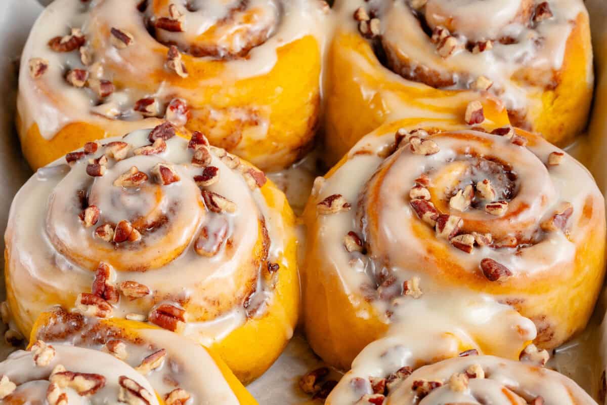 close up of vegan pumpkin cinnamon rolls with icing