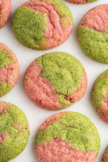 overhead photo of marbled pink and green cookies on a white marble board