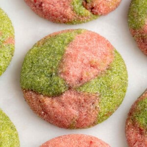 overhead photo of marbled pink and green cookies on a white marble board