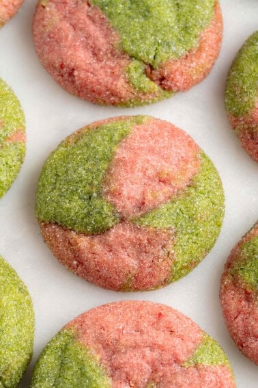 overhead photo of marbled pink and green cookies on a white marble board