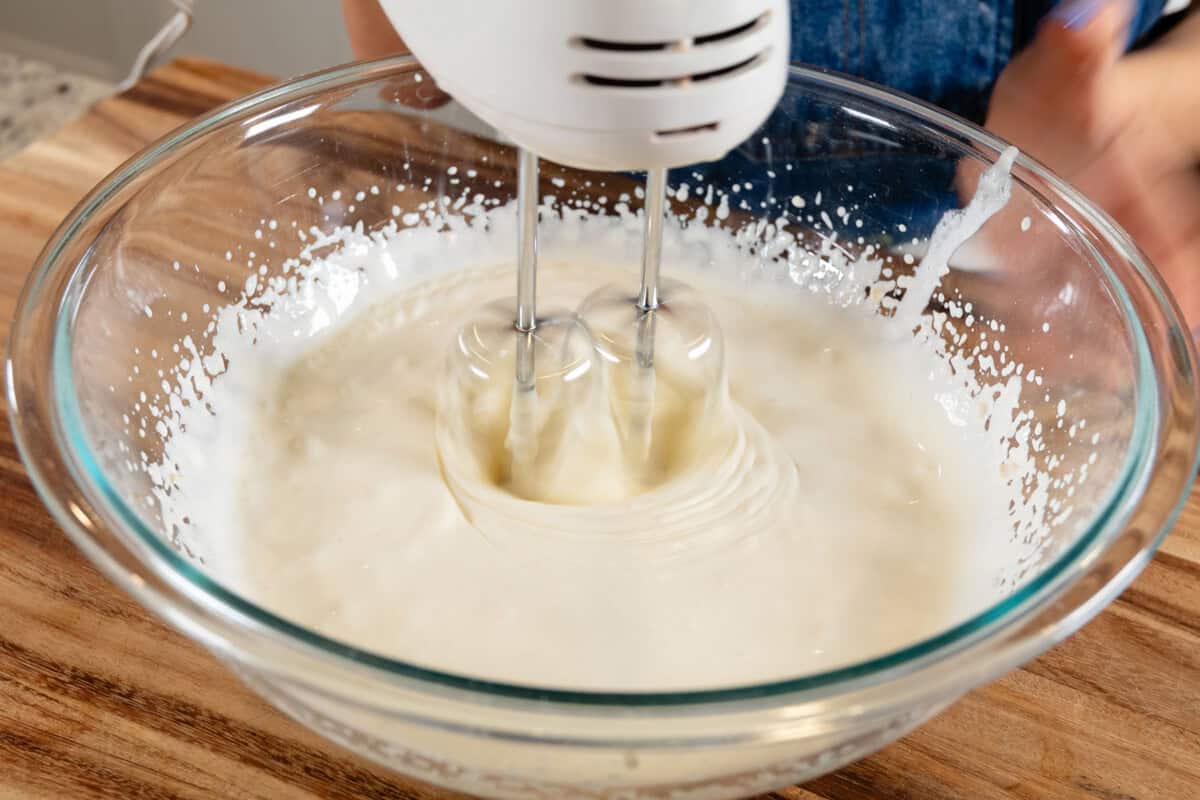 beating heavy cream with a hand mixer in a larger bowl