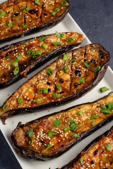 roasted miso-glazed eggplant on white serving plate with sesame seeds and green onion