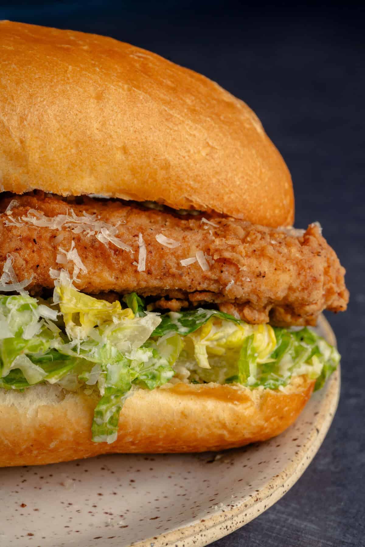close up of tofu fried chicken caesar salad sandwich on a plate
