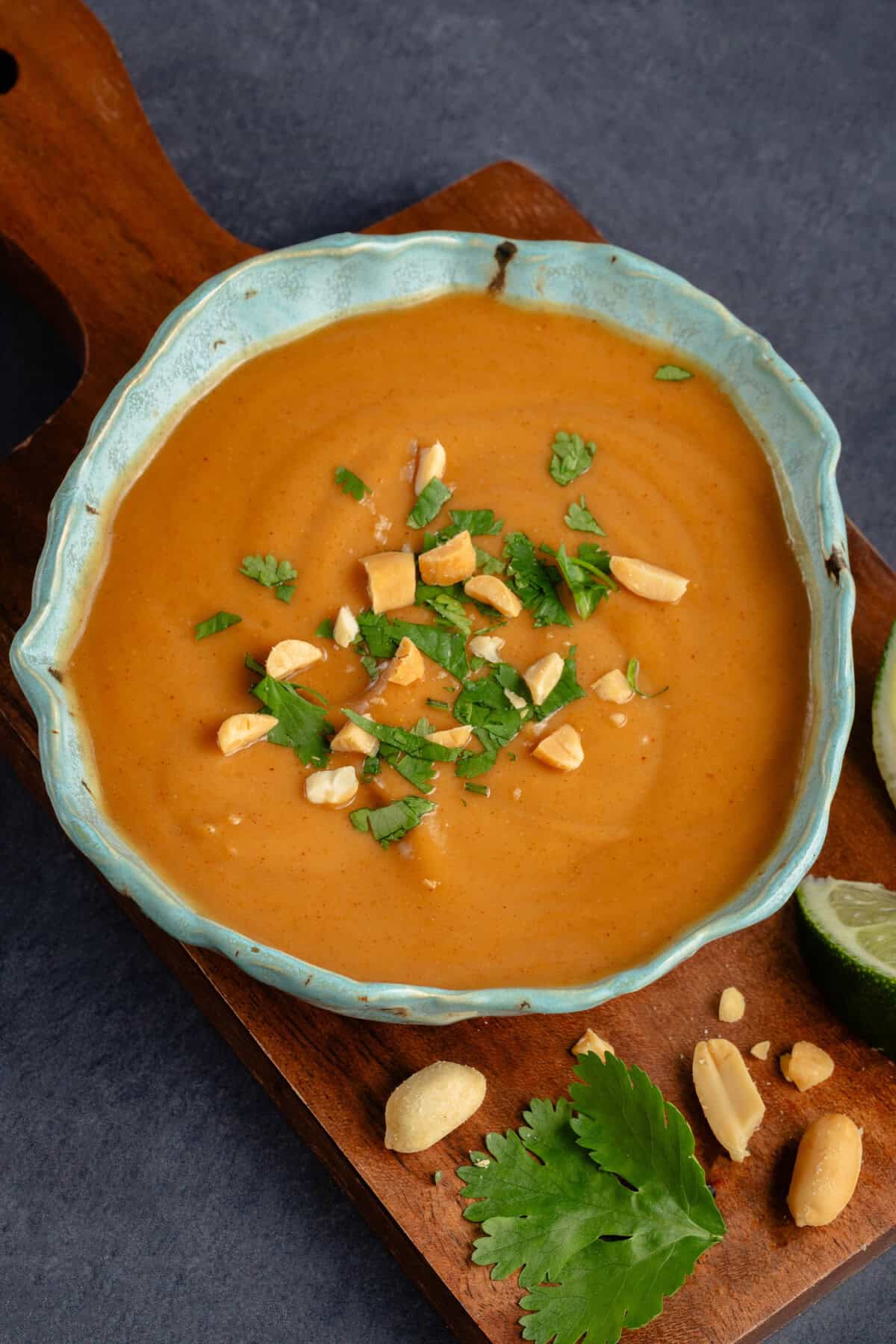 peanut sauce topped with cilantro and roasted peanuts in blue speckled bowl