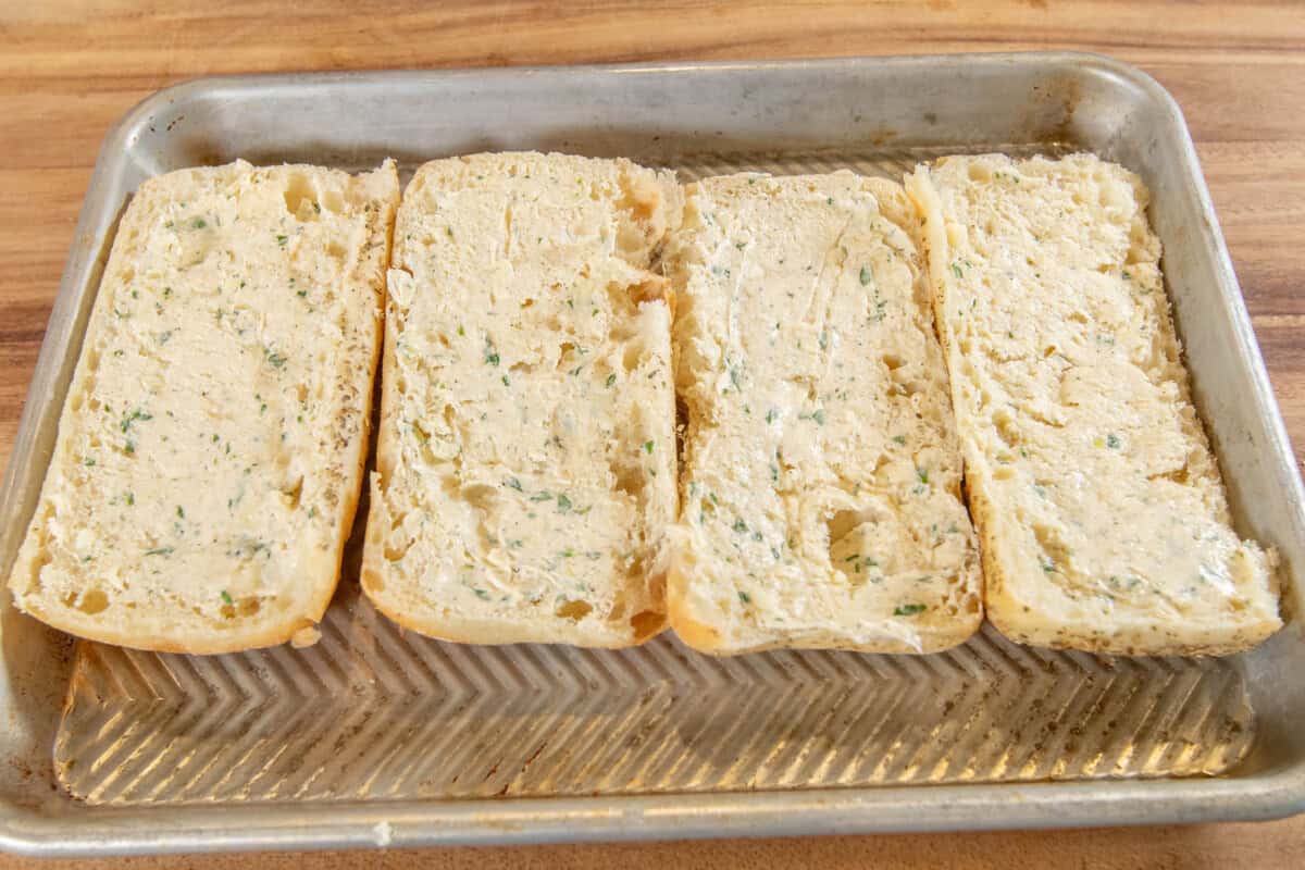 bread coated with the garlic butter on a baking sheet