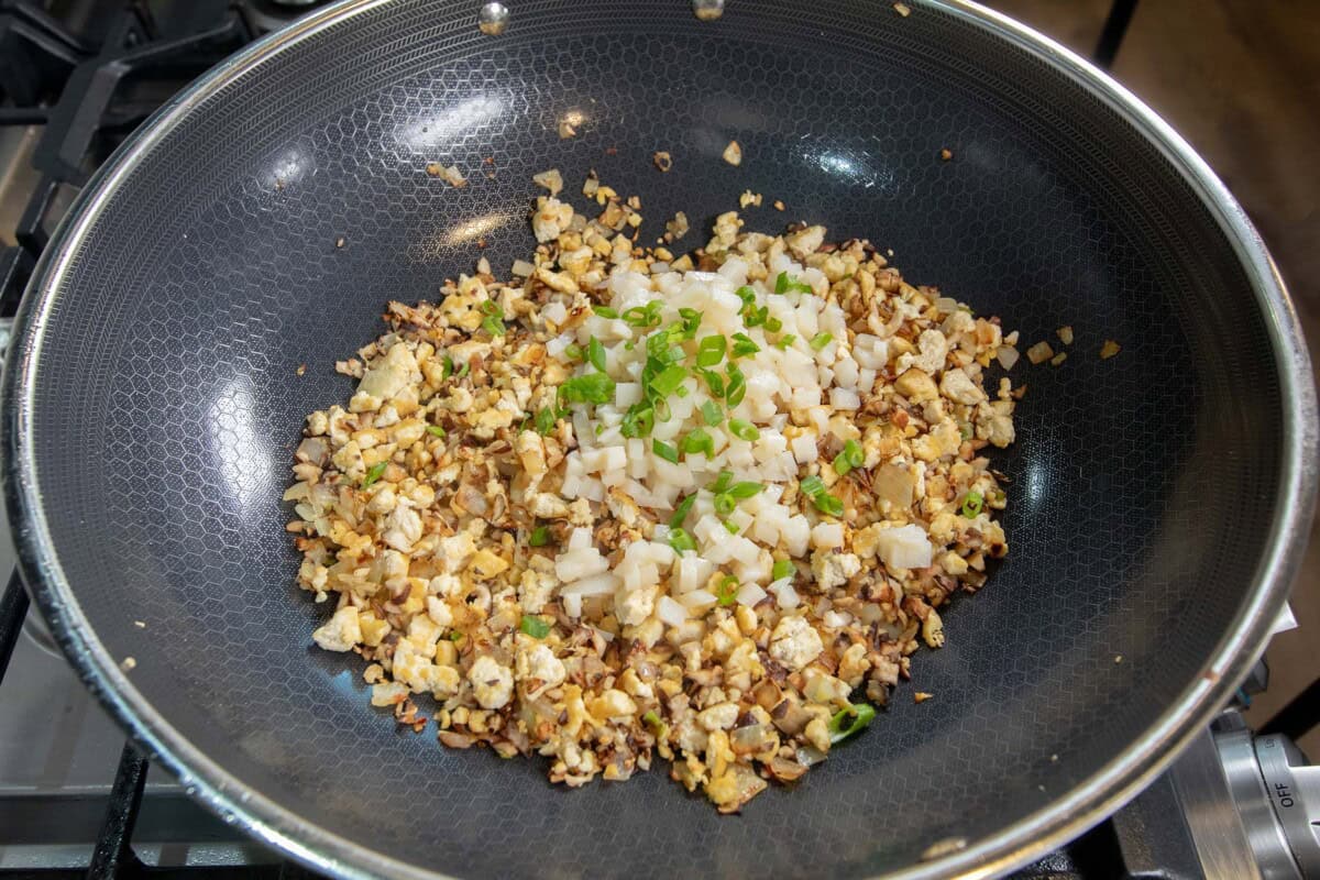 adding water chestnuts and green onions to large skillet