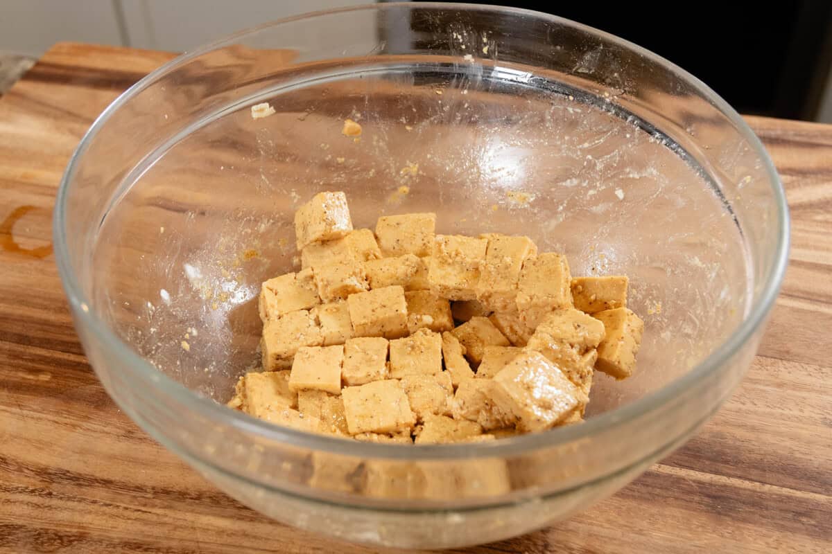 seasoned cubes of extra firm tofu in glass bowl before cooking