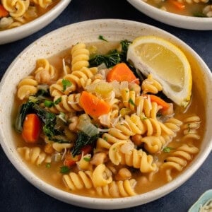 chickpea noodle soup in a bowl with a lemon wedge