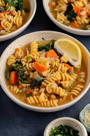 chickpea noodle soup in a bowl with a lemon wedge