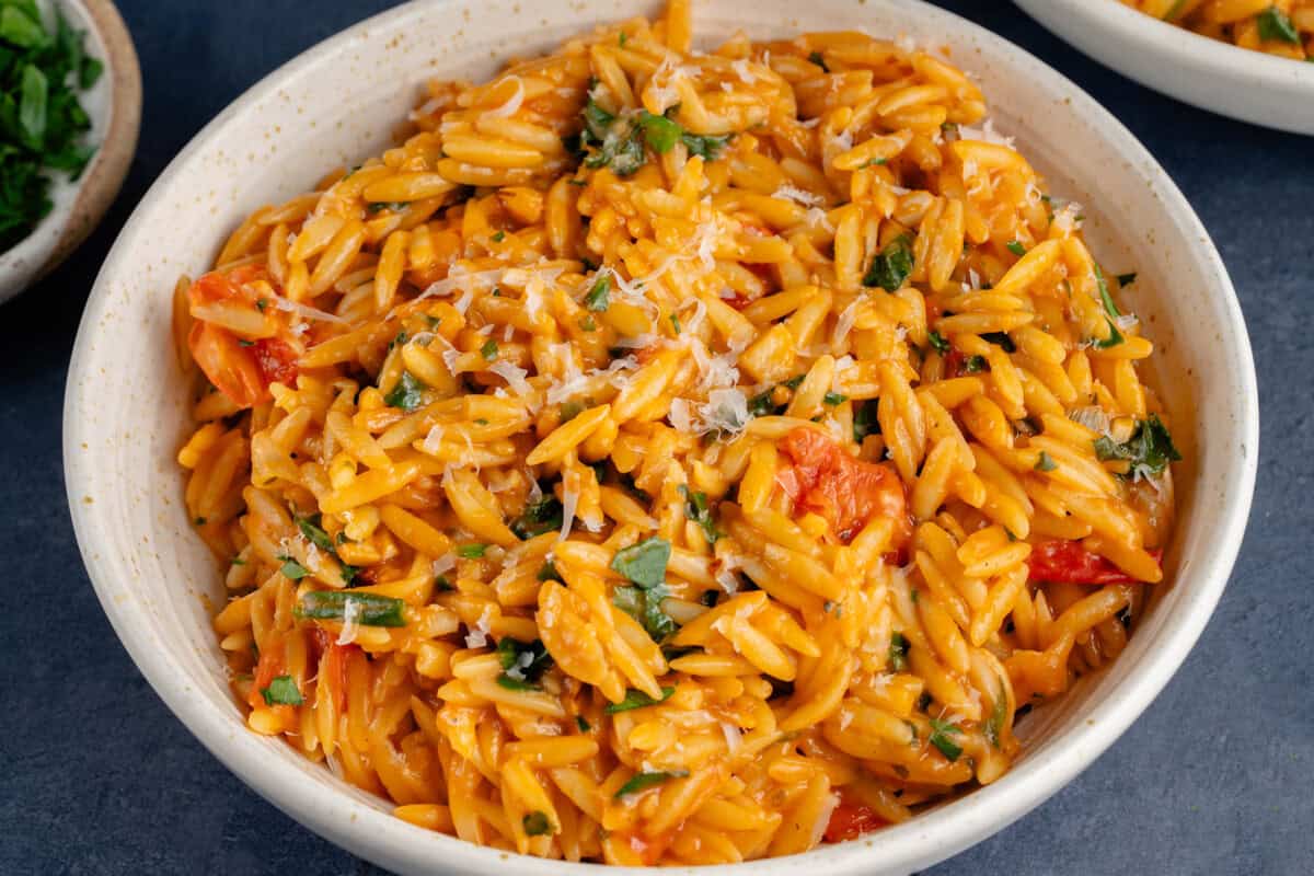 bowl of one pot creamy tomato orzo topped with vegan parmesan