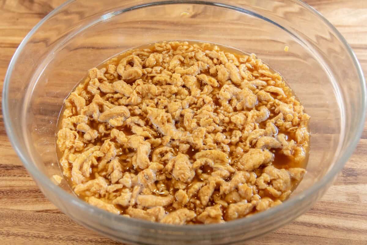 rehydrating soy curls with vegan beef broth in a large bowl