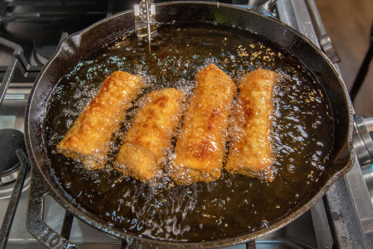 golden crispy cheesesteak egg rolls being fried
