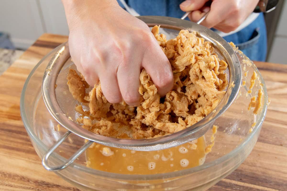 squeezing out the soy curls in a strainer