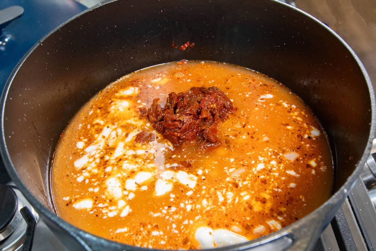 adding cream, both, and sun dried tomatoes to the pot