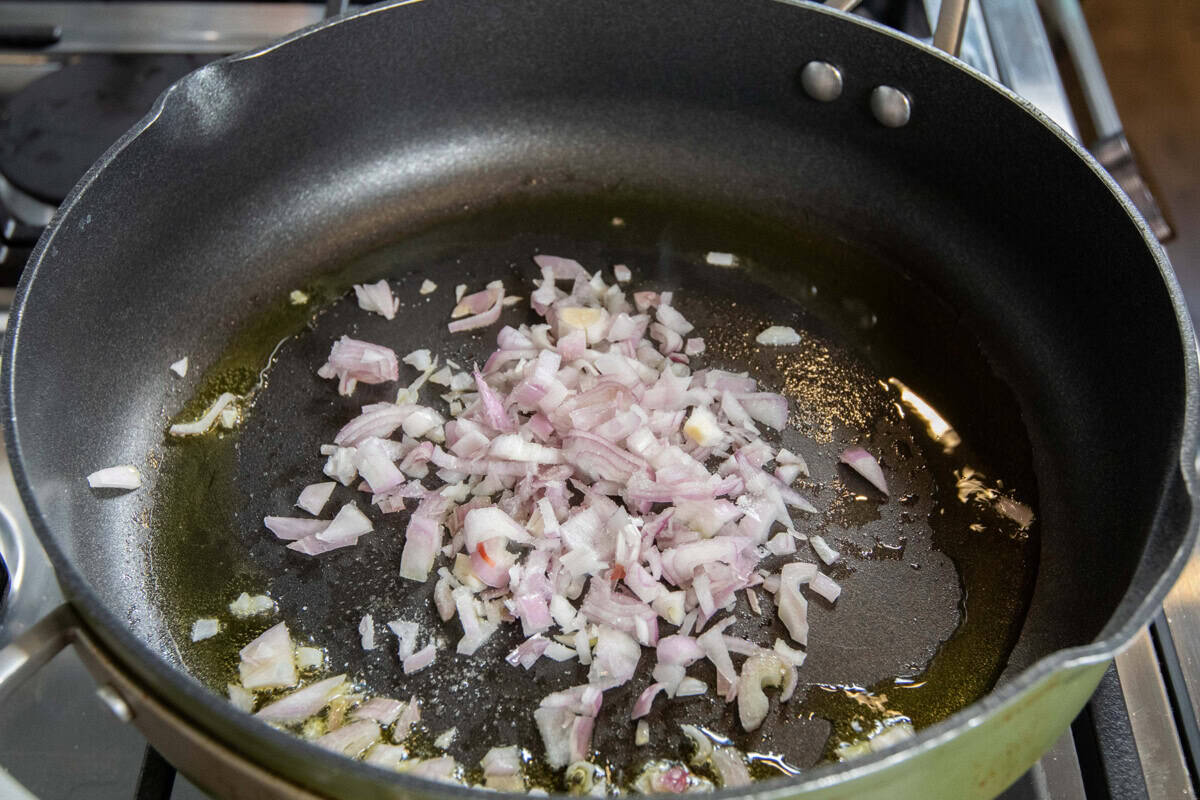 adding shallots to pan with oil