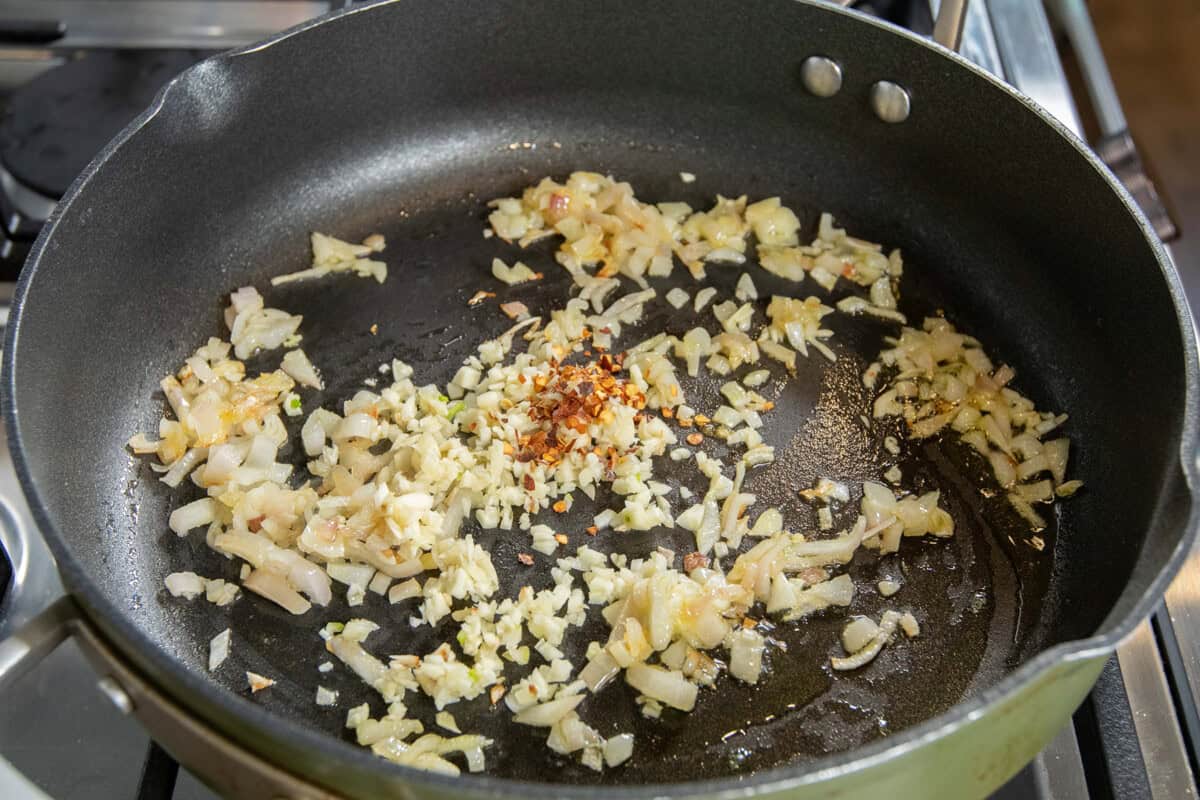 adding onions, garlic, and red pepper flakes to the pan