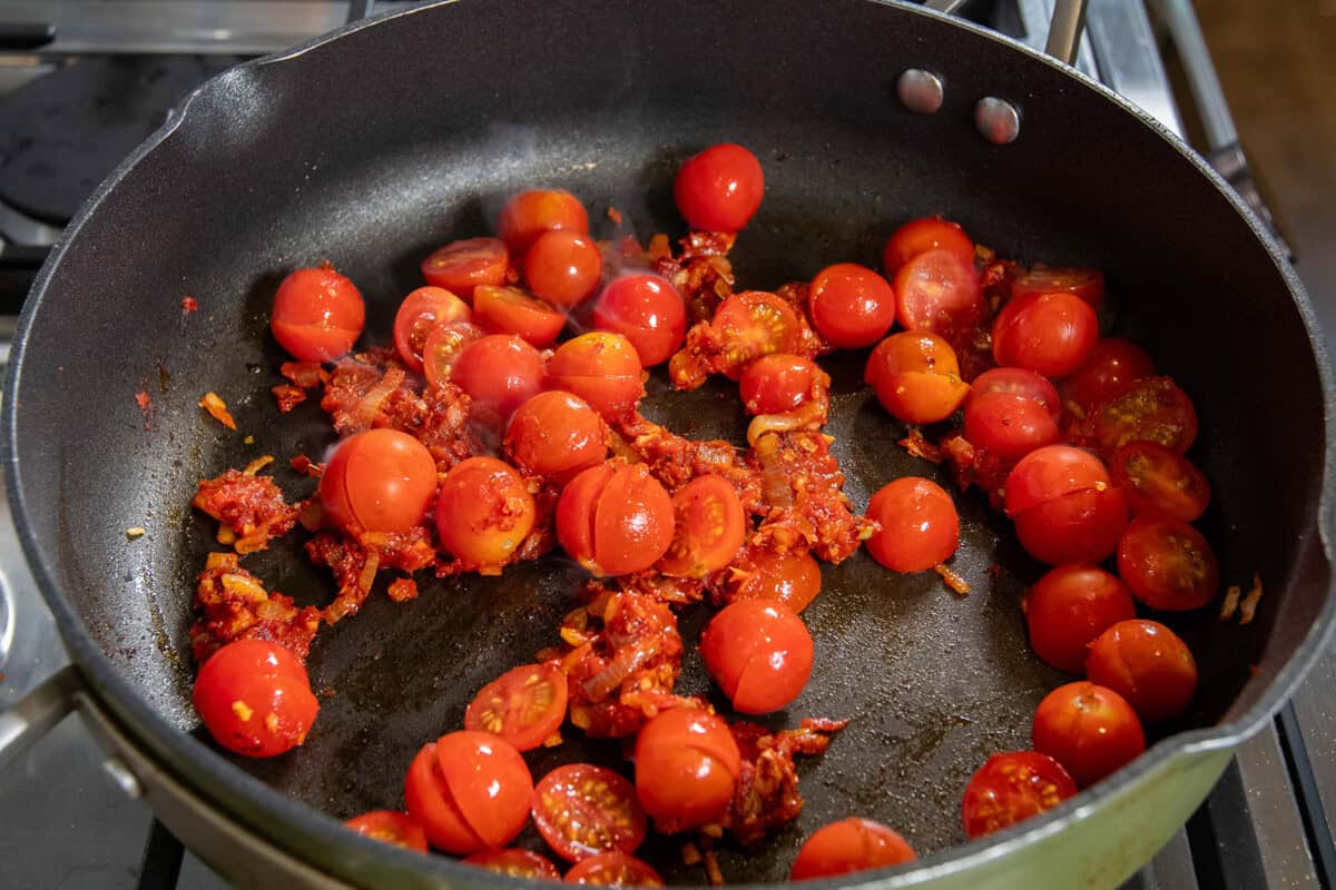 adding fresh tomatoes to the pan