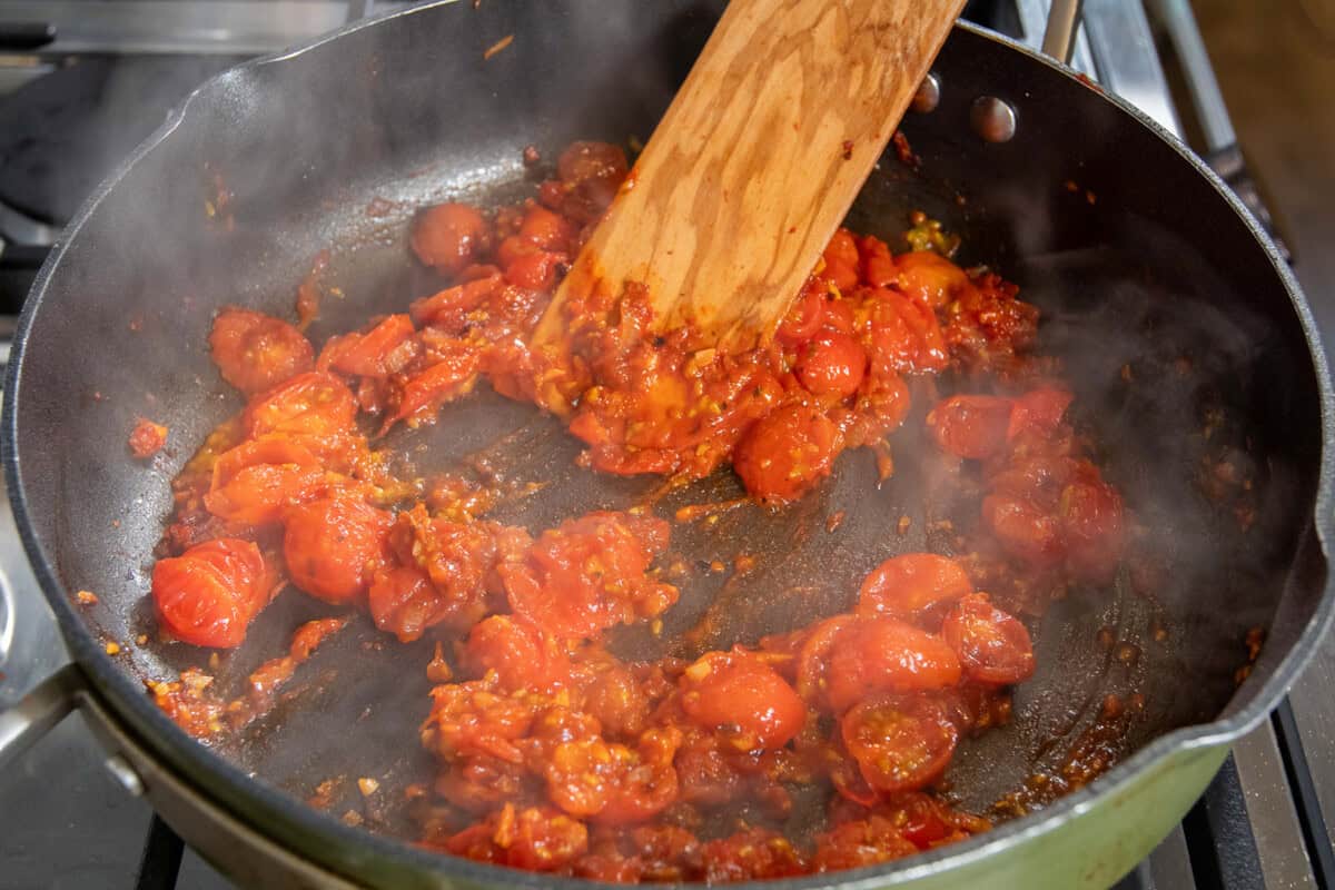 cooking tomatoes in aromatics and herbs