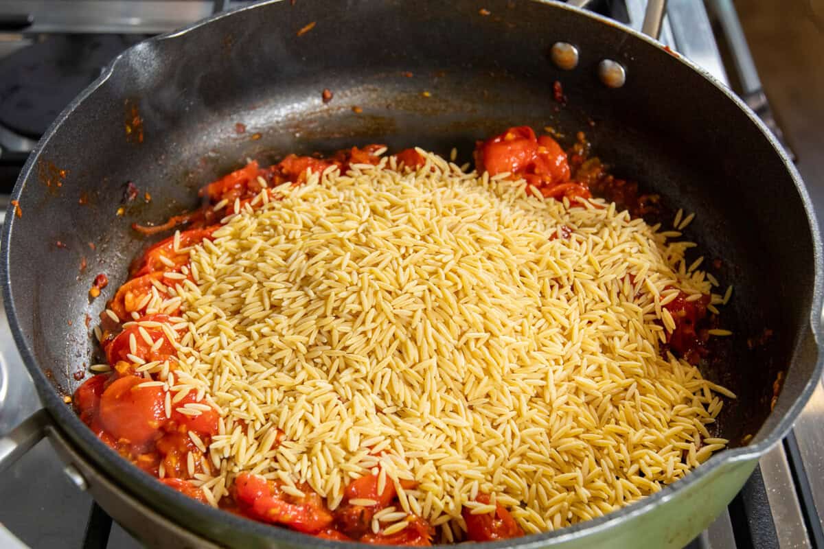 adding orzo to the pan