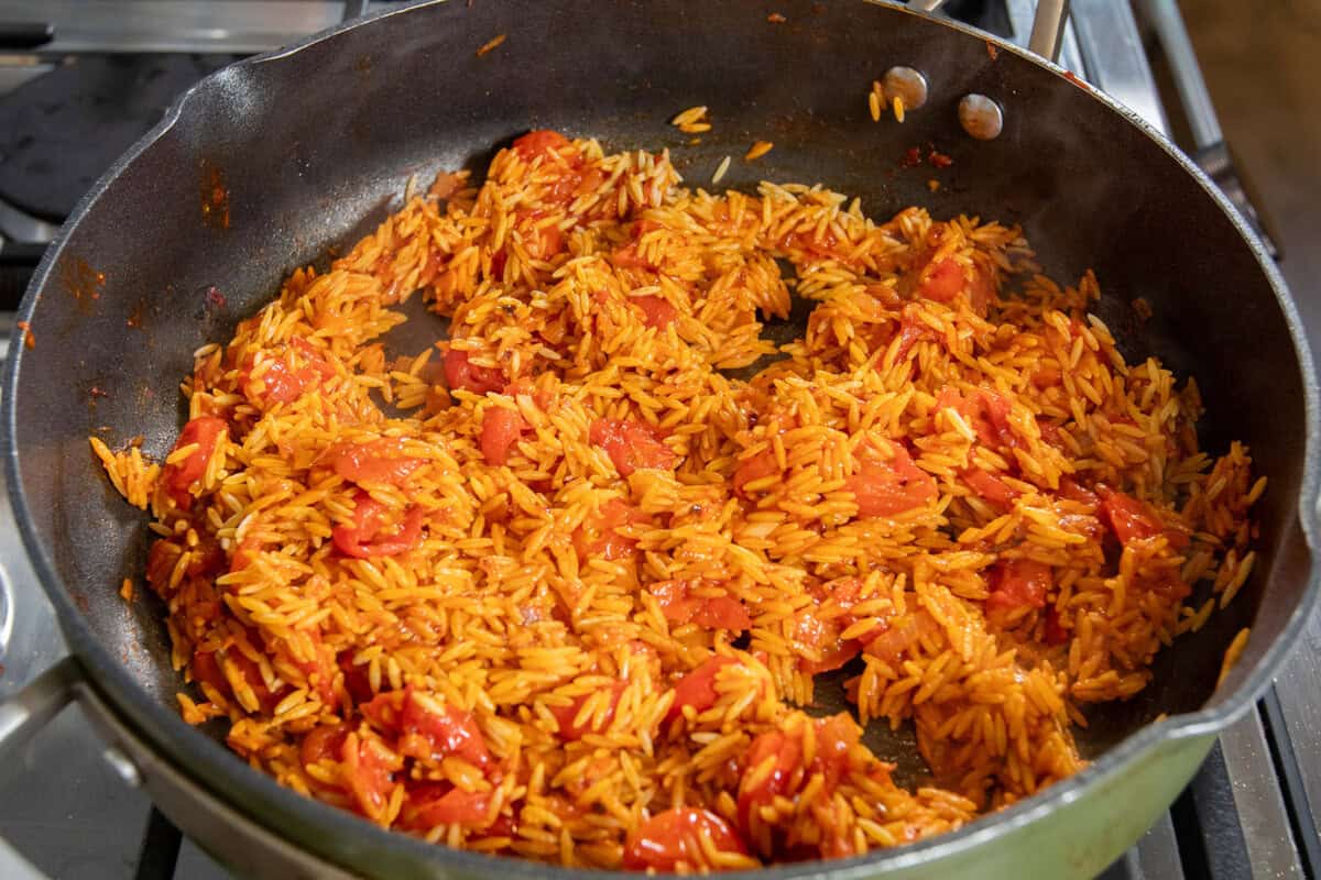 toasting the orzo in the in the pan with tomatoes