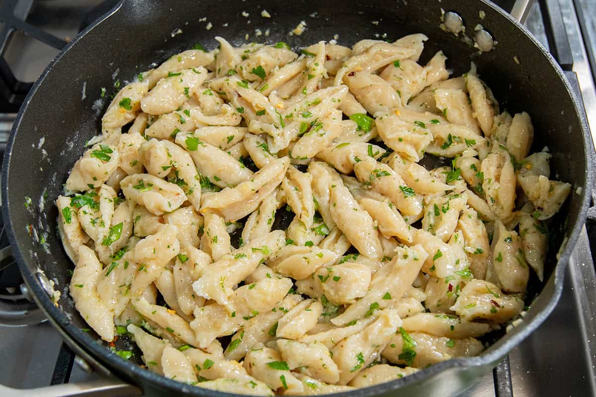 pan full of tofu pasta with garlic, herbs, and olive oil