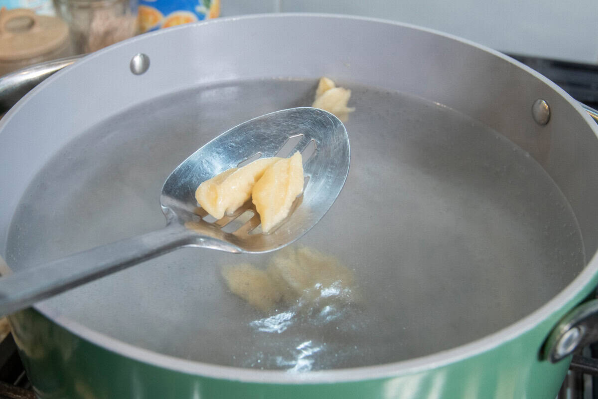 scooping finished pasta from a pot of boiling water