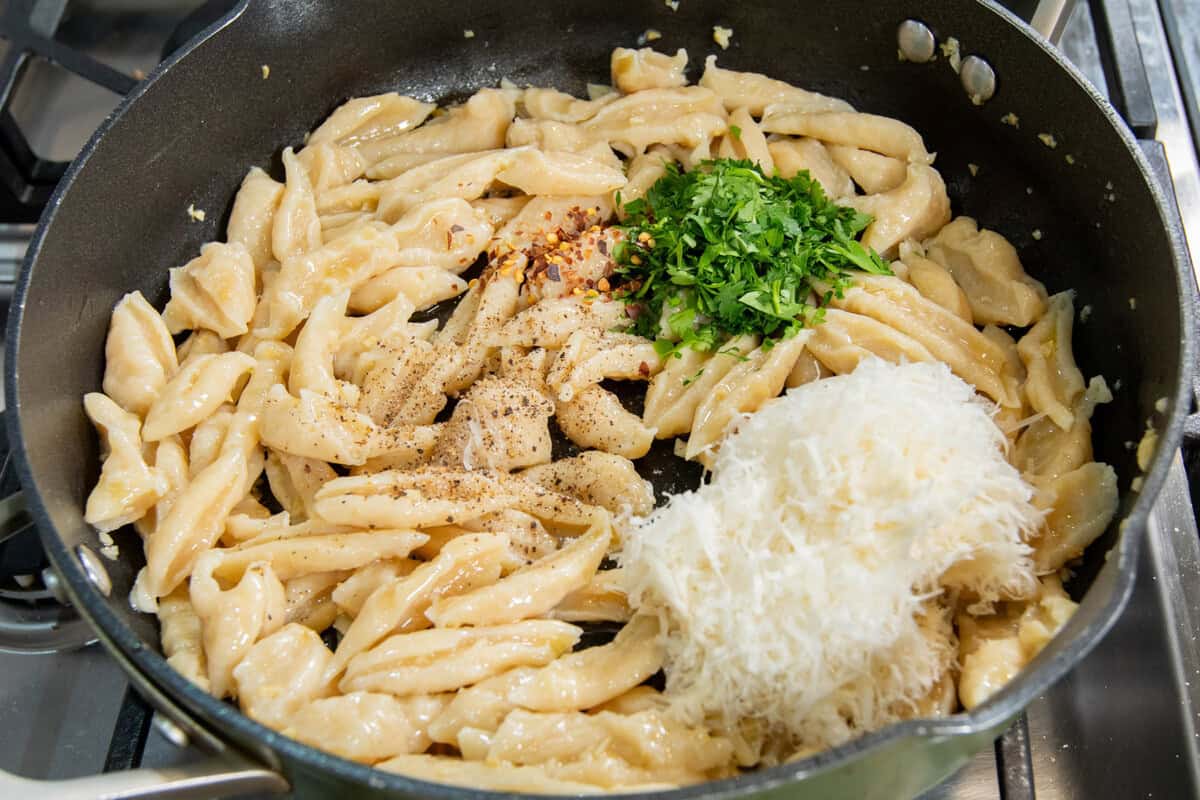 pan full of 3-ingredient tofdu pasta, vegan parmesan, herbs. salt, pepper, and red pepper flakes