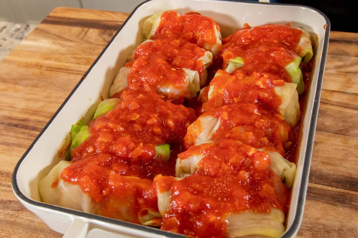 stuffed cabbage rolls lined in a baking dish topped with tomato sauce