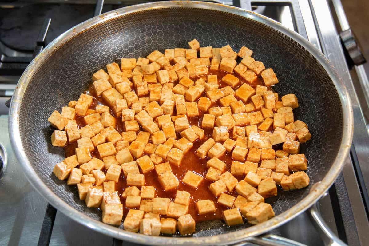 sauce added to cubed tofu in a pan