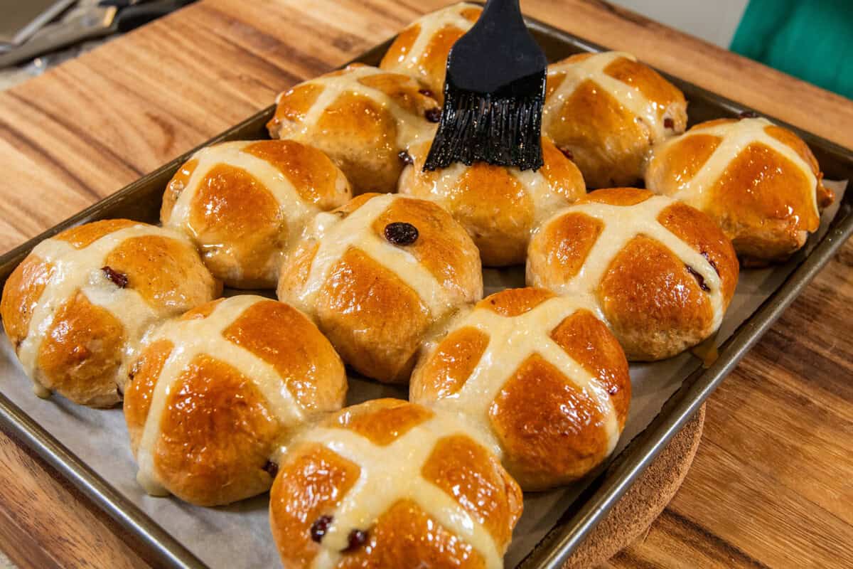 brushing the vegan hot cross buns with apricot jam after baking