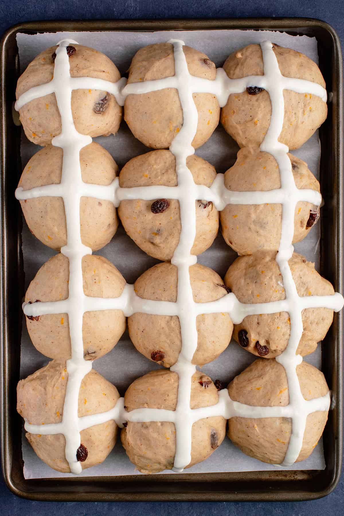 unbaked vegan hot cross buns on a lined baking sheet