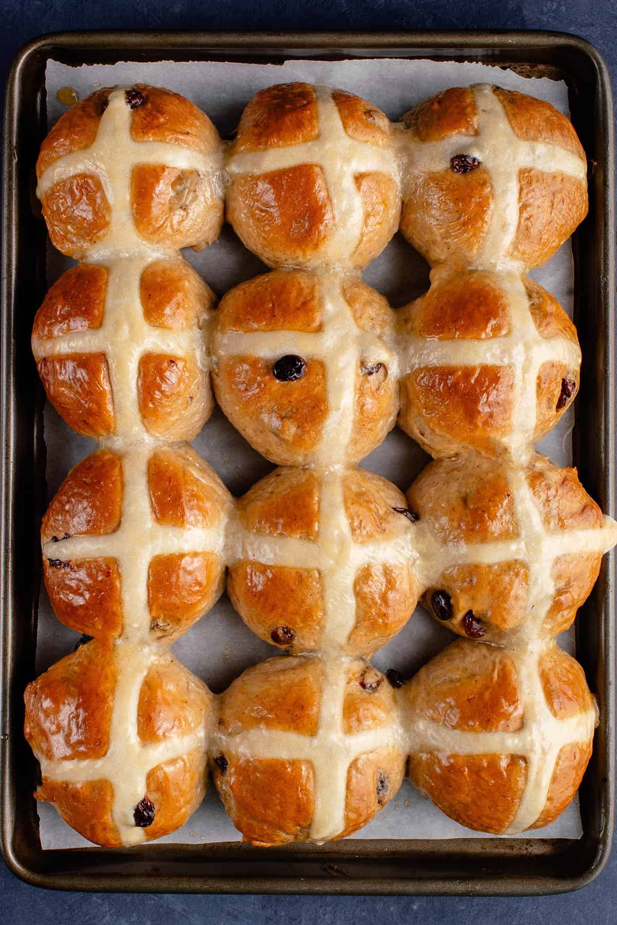 vegan hot cross buns on a lined baking sheet