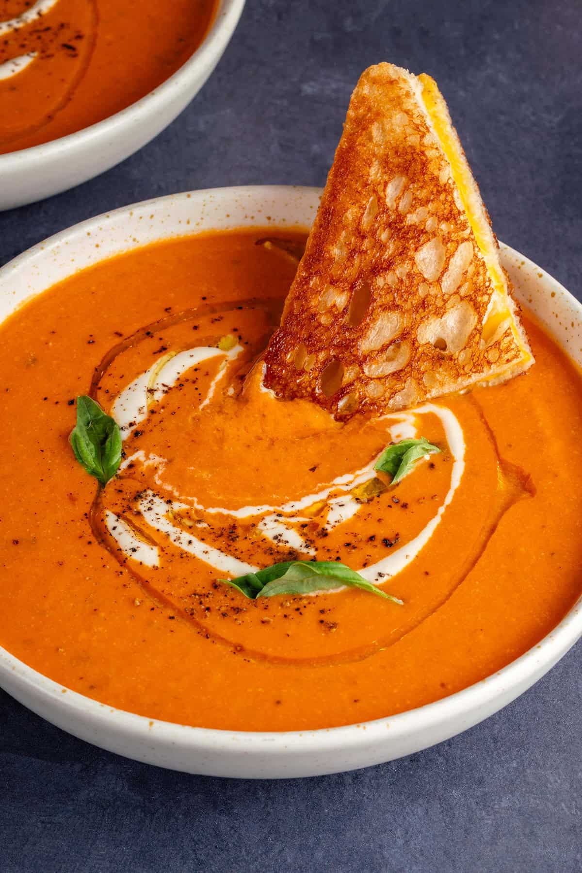 bowl of creamy vodka tomato soup garnished with grilled cheese