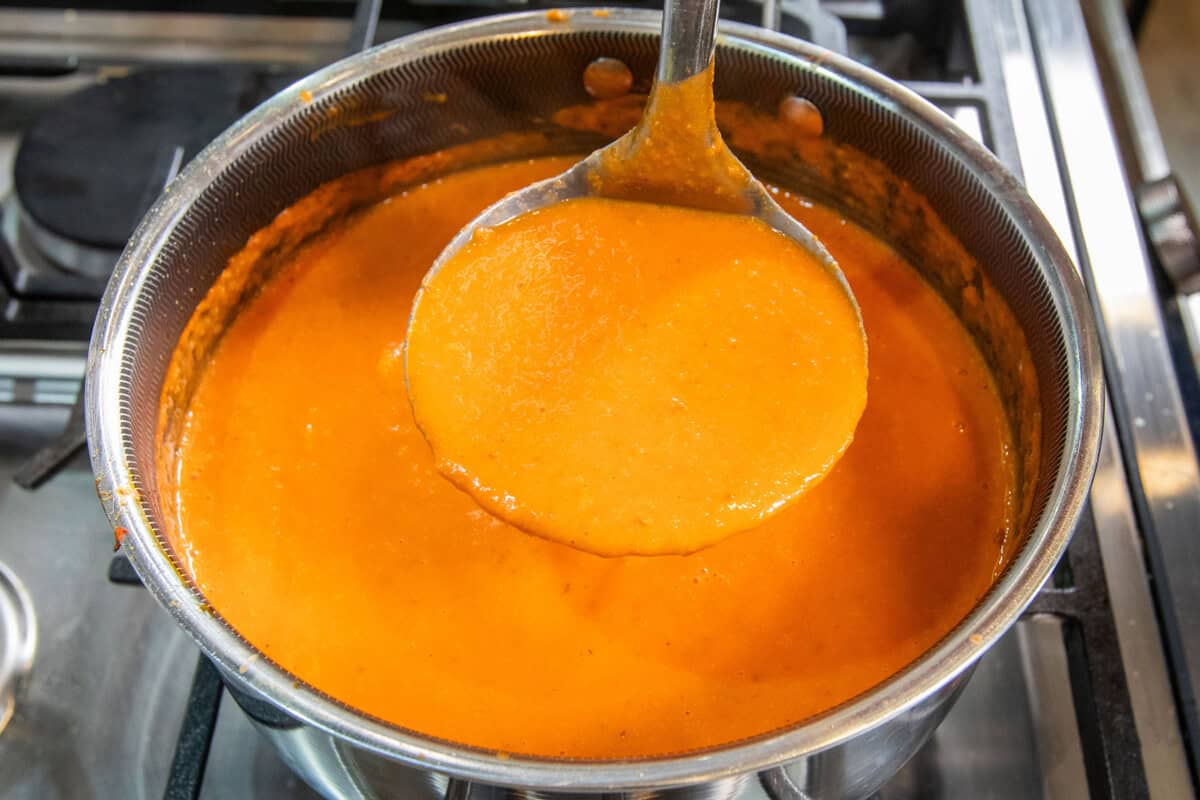 ladle full of creamy vodka tomato soup in pot