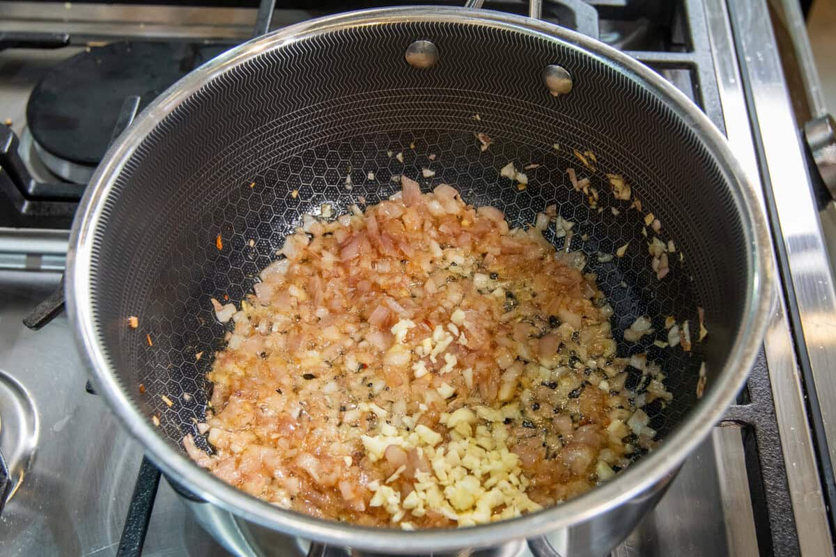 adding garlic to pot of cooked shallots