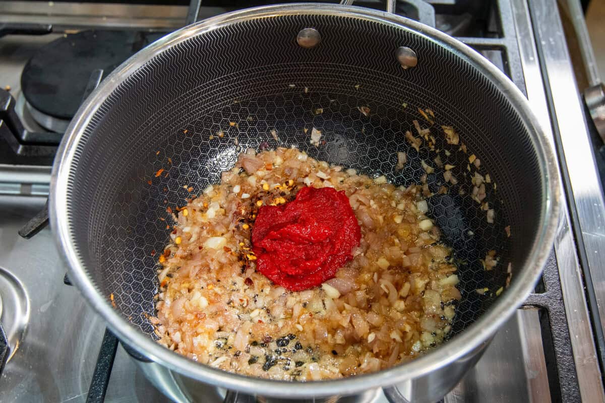 adding tomato pasted to sautéed shallots and garlic