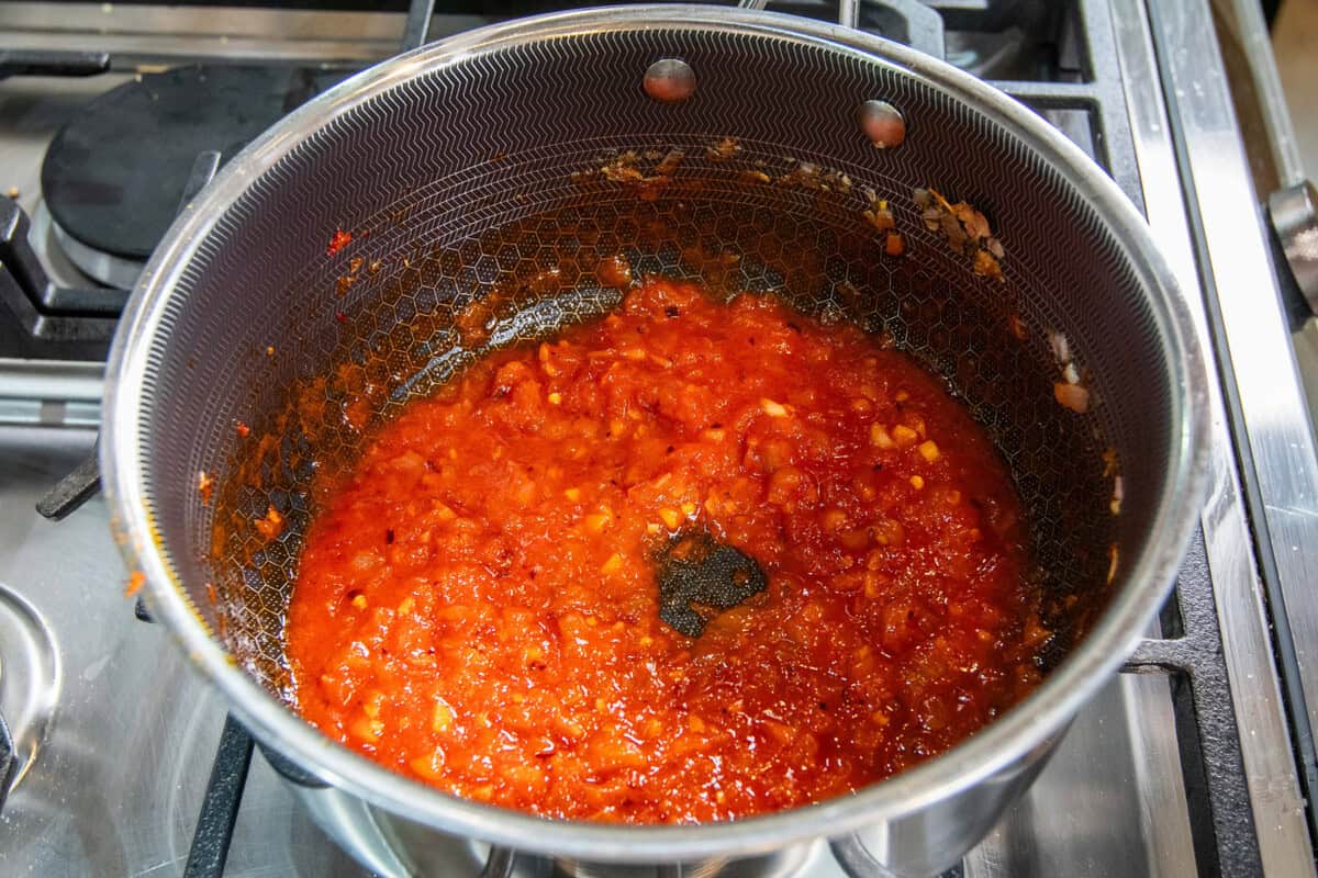 cooking down tomato paste in pot with shallots and garlic