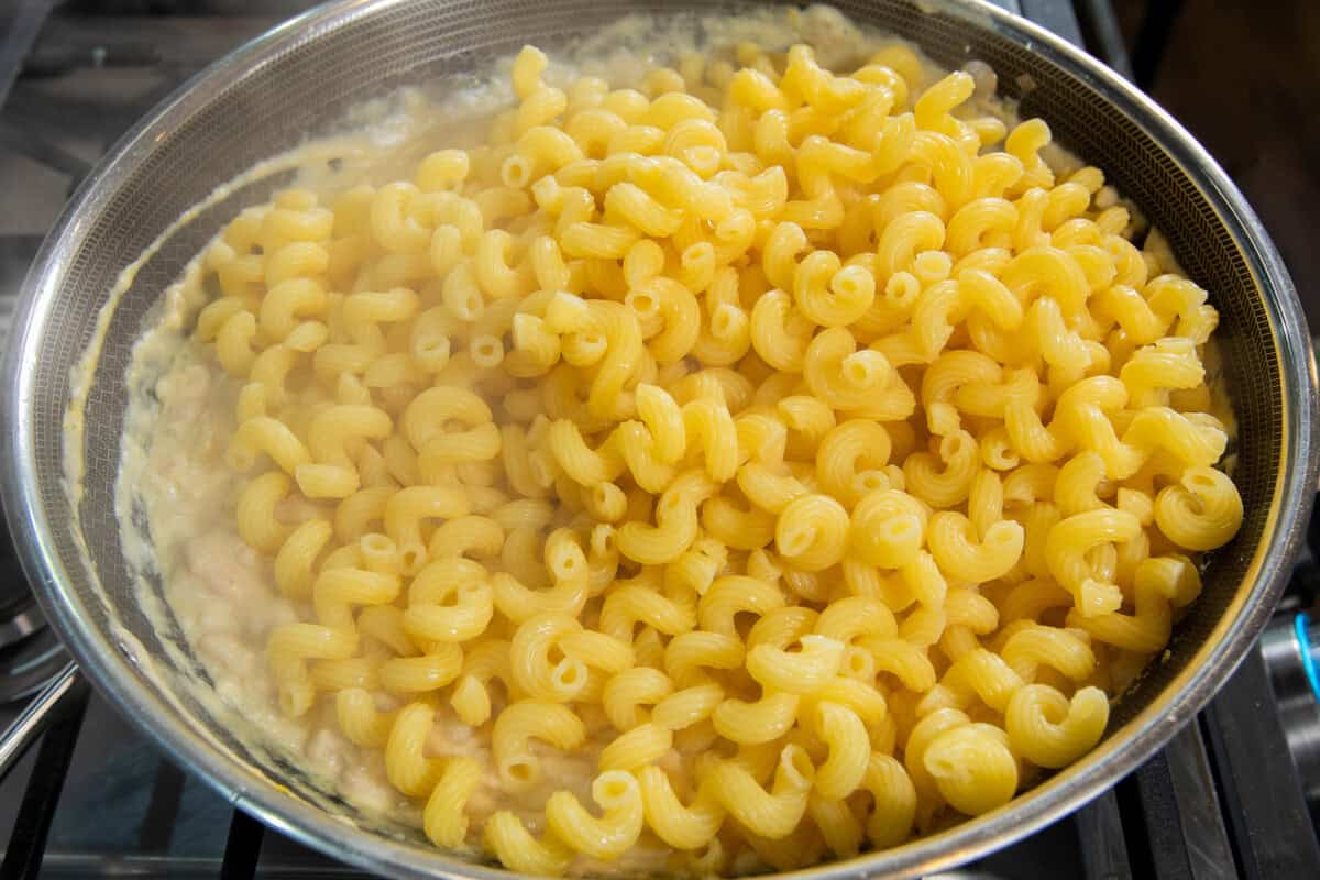 adding pasta to pot with creamy sauce