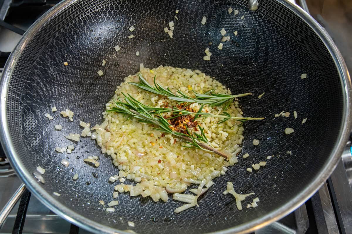 adding rosemary and red pepper flake to sautรฉing shallots and garlic