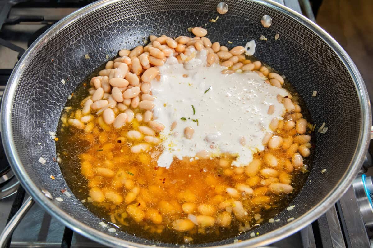 adding broth, beans, and cashew cream to pot