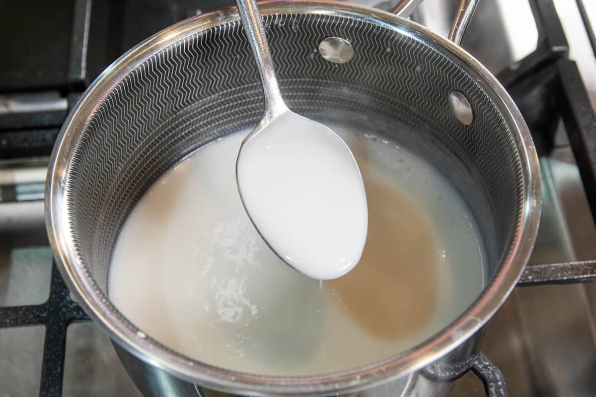 spooning the sauce from the pot