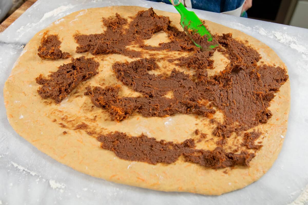 spreading cinnamon roll filling on the dough