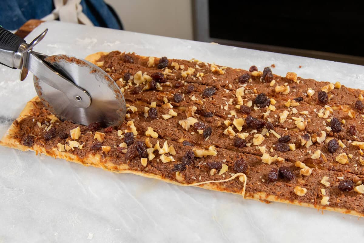 slicing strips of dough for the cinnamon rolls